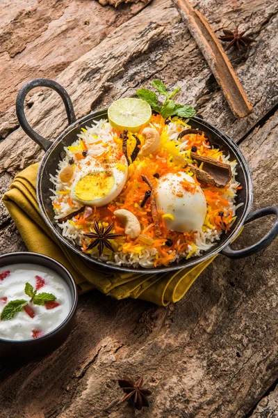 Basmati rice slowly cooked with Masala roasted egg and spices served in kadhai or kadai with yogurt dip, selective focus, egg biryani or anda rice or egg rice