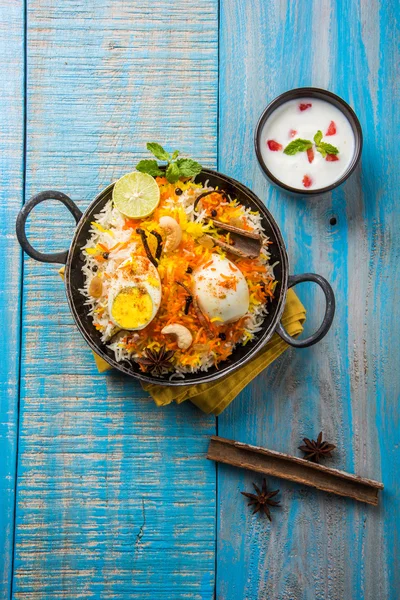 Basmati rice slowly cooked with Masala roasted egg and spices served in kadhai or kadai with yogurt dip, selective focus, egg biryani or anda rice or egg rice