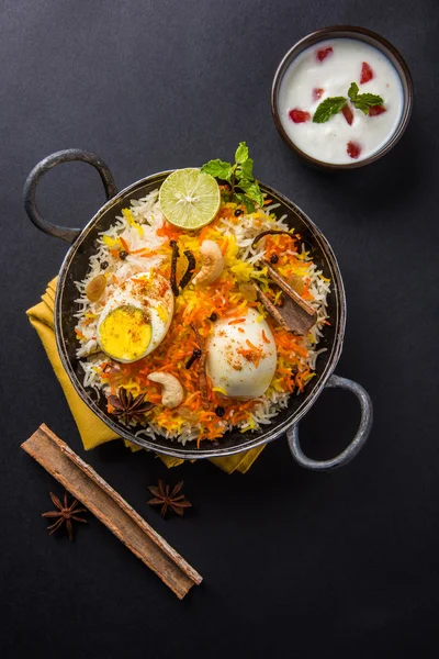 Basmati rice slowly cooked with Masala roasted egg and spices served in kadhai or kadai with yogurt dip, selective focus, egg biryani or anda rice or egg rice