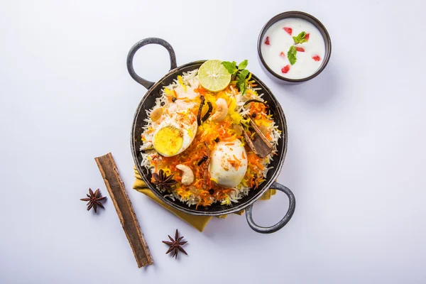 Basmati rice slowly cooked with Masala roasted egg and spices served in kadhai or kadai with yogurt dip, selective focus, egg biryani or anda rice or egg rice