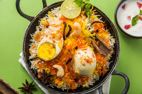 Basmati rice slowly cooked with Masala roasted egg and spices served in kadhai or kadai with yogurt dip, selective focus, egg biryani or anda rice or egg rice