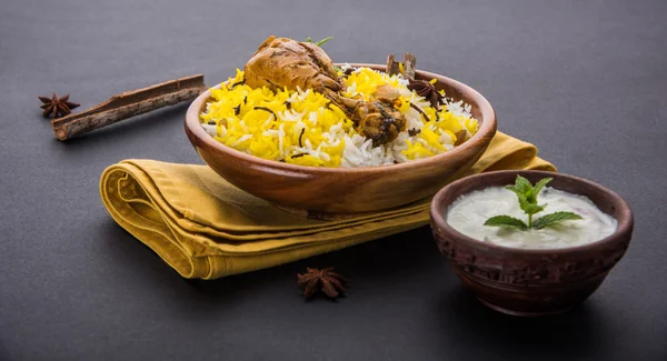 Chicken Biryani with yogurt dip on beautiful moody background, selective focus