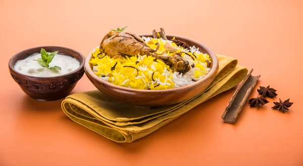 Chicken Biryani with yogurt dip on beautiful moody background, selective focus