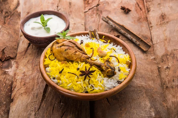 Chicken Biryani with yogurt dip on beautiful moody background, selective focus