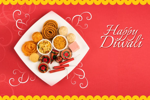 Diwali greeting card made using Diwali mithai like jalebi, bundi laddu, burfi and pera with Diwali snacks like chivda, sev, chakli served with Diwali firecrackers or fire crackers