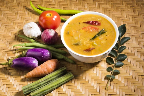 South indian vegetable sambar, with vegetables isolated on wooden ken background