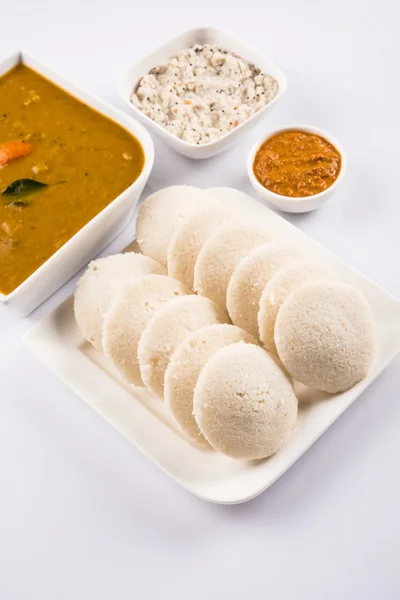 Traditional south indian food, idli or idly with sambar and white coconut chutney and red chutney in white ceramic square plate and bowl on white background, front view isolated on white background