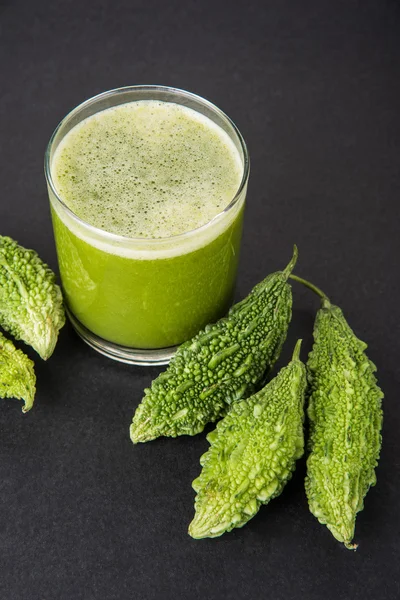 Herbal juice of green momodica in a glass with sliced vegetables, karela juice or bitter gourd juice