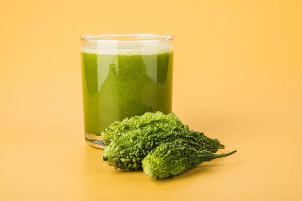 Herbal juice of green momodica in a glass with sliced vegetables, karela juice or bitter gourd juice