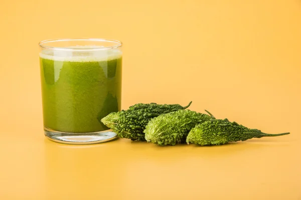 Herbal juice of green momodica in a glass with sliced vegetables, karela juice or bitter gourd juice