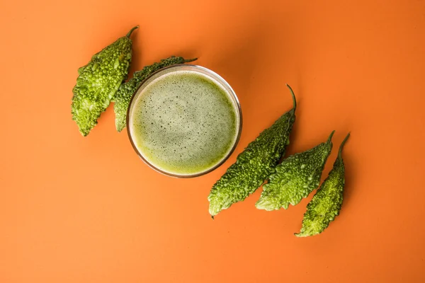 Herbal juice of green momodica in a glass with sliced vegetables, karela juice or bitter gourd juice