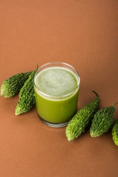 Herbal juice of green momodica in a glass with sliced vegetables, karela juice or bitter gourd juice