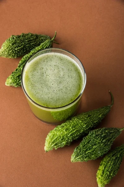 Herbal juice of green momodica in a glass with sliced vegetables, karela juice or bitter gourd juice