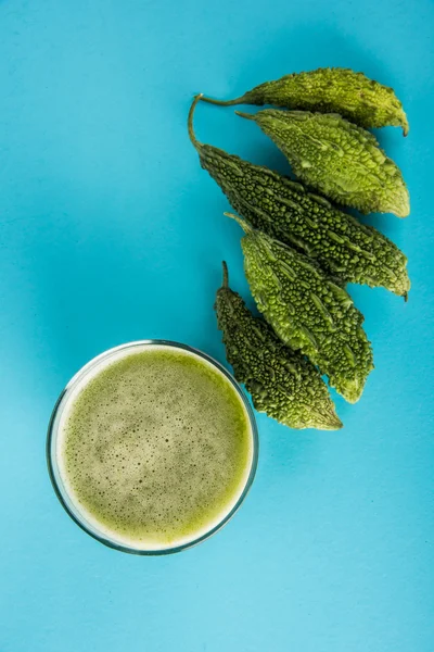 Herbal juice of green momodica in a glass with sliced vegetables, karela juice or bitter gourd juice