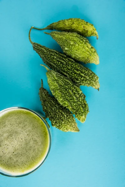 Herbal juice of green momodica in a glass with sliced vegetables, karela juice or bitter gourd juice