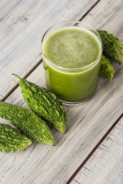 Herbal juice of green momodica in a glass with sliced vegetables, karela juice or bitter gourd juice