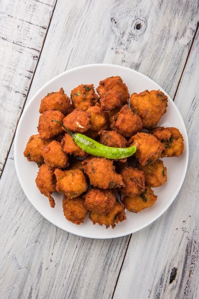 Delicious Tasty and Yummy Indian Moong Dal vada or moong dal pakoda or moong vada or moong vade or Pakora or pakode (Fritter) with fried green chilli, red and green hot sauce.