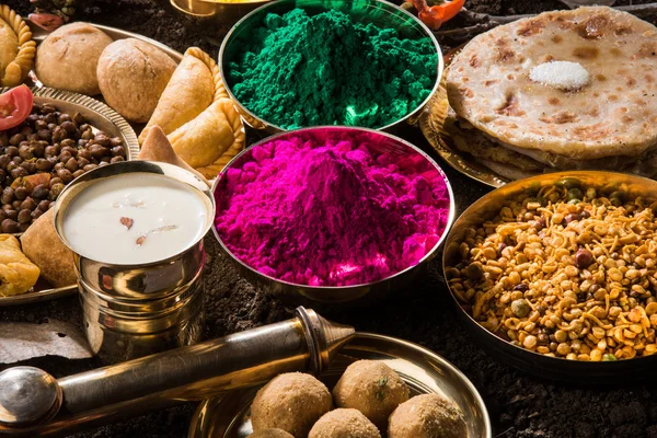 Holi festival food with colours, indian festival holi, samosa, kachori, laddu, gujiya, palash flower, thandai, farsan, puran poli or roti, indian festival of colours called holi