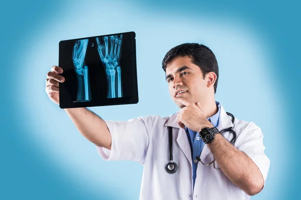 Young indian male doctor with x ray or MRI , asian male doctor with xray or xray, isolated on blue background