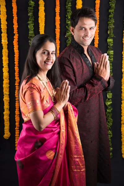 Indian young couple praying in traditional cloths, indian newly married couple in namaskar or welcoming pose or prayer pose