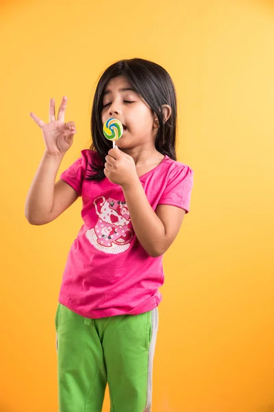 Indian small girl with lolipop or loly pop, asian girl and lolipop or lolypop, playful indian cute girl posing with lolipop or candy