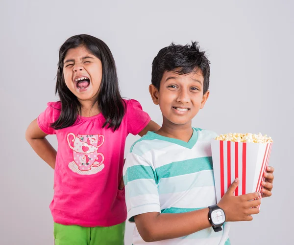 Different moods while small indian girl child and boy eating popcorn