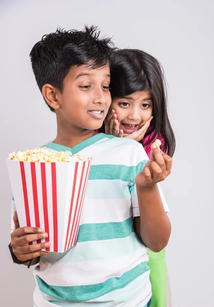 Different moods while small indian girl child and boy eating popcorn