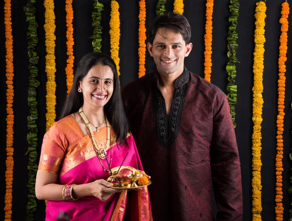 Portrait of Maharashtrian couple holding a puja thali, indian couple holding puja thali or pooja thali, indian couple celebrating diwali, laxmi pujan, asian couple and puja thali, couple doing prayer