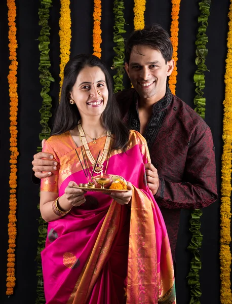 Portrait of Maharashtrian couple holding a puja thali, indian couple holding puja thali or pooja thali, indian couple celebrating diwali, laxmi pujan, asian couple and puja thali, couple doing prayer