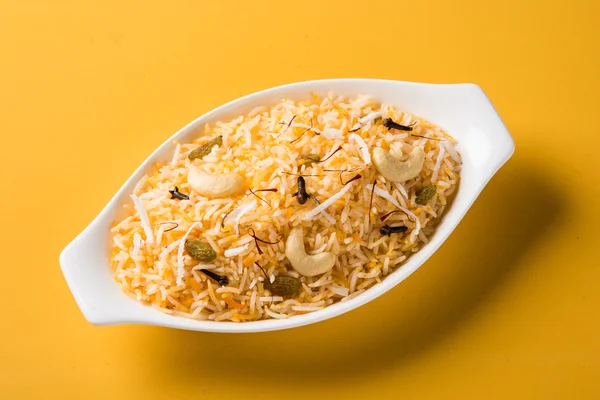 Coconut rice, coconut sweet rice, sweet coconut rice also known as narali bhat in marathi, favourite Indian sweet, konkan food, kerala food, saffron, cashew, cloves, served in white bowl, isolated