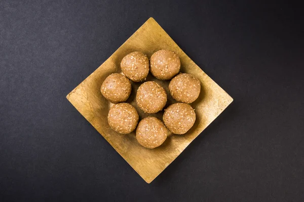 The indian sesame sweet or tilgul laddu, made up of jaggery and sesame seeds, indian sweet for Makar Sankranti festival, in terracotta bowl with jaggery & raw sesame