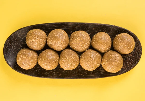 The indian sesame sweet or tilgul laddu, made up of jaggery and sesame seeds, indian sweet for Makar Sankranti festival, in terracotta bowl with jaggery & raw sesame