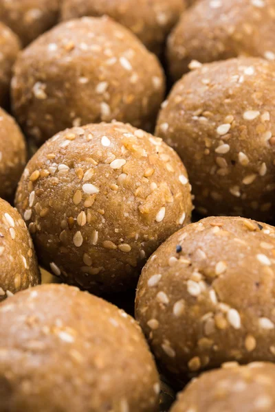 Sesame laddu or tulgul or til gul laddu or ladu in brass plate with huldi and kumkum, indian traditional festival in january, indian sweet food, indian rituals, tilgul cake or vadi