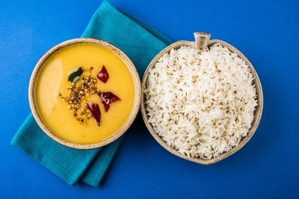 Whole Yellow Lentil with Rice, dal tadka and jeera rice, Indian Dish, cooked rice and cooked Arhar or Toor dal (Pigeon Pea), served in ceramic bowl, on green mat