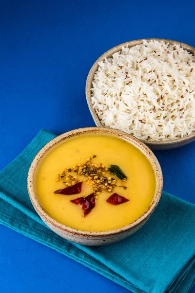 Whole Yellow Lentil with Rice, dal tadka and jeera rice, Indian Dish, cooked rice and cooked Arhar or Toor dal (Pigeon Pea), served in ceramic bowl, on green mat