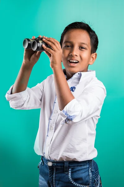 Little indian kid using binoculars, little asian kid using binoculars, indian Boy with binoculars, Curious little boy with binoculars, isolated on green background