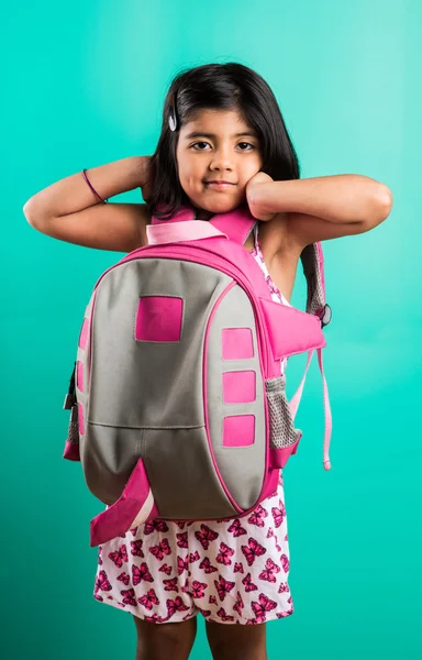 4 year old happy little indian girl standing with school bag on her back with casual dressing, isolated on green background, little asian girl with school bag, school bag and little girl