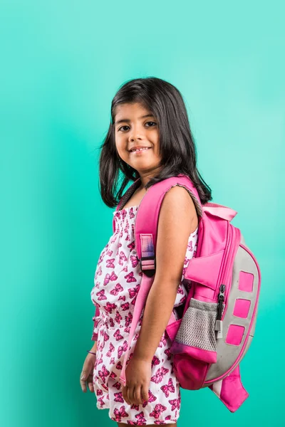 4 year old happy little indian girl standing with school bag on her back with casual dressing, isolated on green background, little asian girl with school bag, school bag and little girl