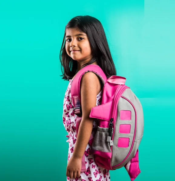 4 year old happy little indian girl standing with school bag on her back with casual dressing, isolated on green background, little asian girl with school bag, school bag and little girl