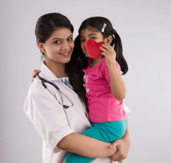 Indian girl child with young beautiful female doctor, indian doctor and baby girl, asian doctor with girl, isolated on gray background