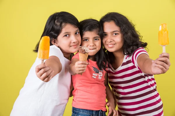 Three cute little indian kids eating ice cream, asian girls and boy and ice cream, isolated on green background