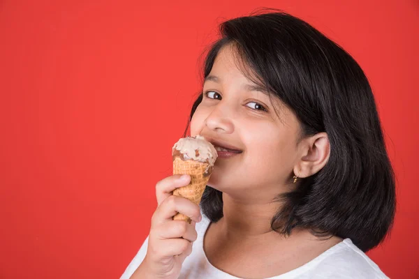 Happy Little Indian girl with an ice candy or ice cream in hand, asian girl and ice cream, isolated on red background