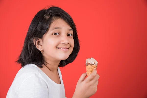 Happy Little Indian girl with an ice candy or ice cream in hand, asian girl and ice cream, isolated on red background