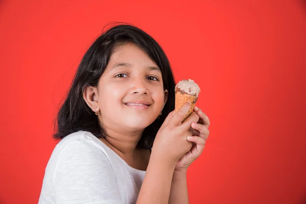 Happy Little Indian girl with an ice candy or ice cream in hand, asian girl and ice cream, isolated on red background