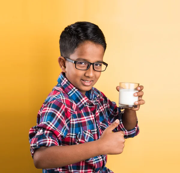 Indian boy with a glass of milk, indian kid drinking milk, indian boy drinking milk,asian boy and milk, closeup portrait on yellow background