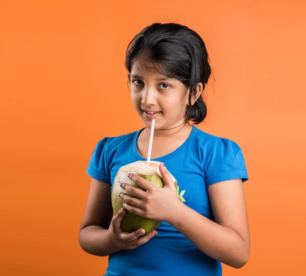 Indian small girl drinking coconut water, asian girl with coconut, indian girl holding coconut with straw, indian girl enjoying coconut water