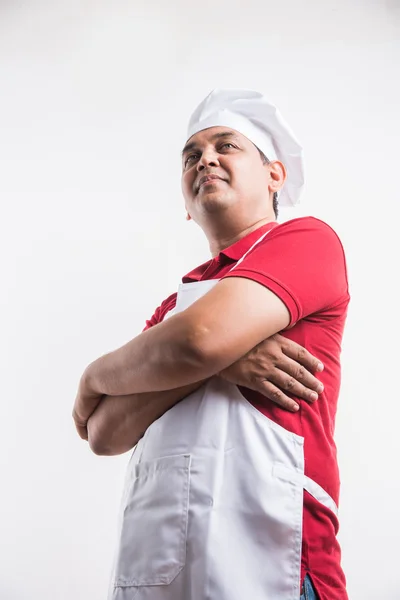 Portrait of handsome and cheerful Indian male chef in uniform with hands folded, isolated over white background, selective focus on eye, copy space