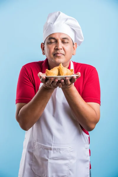 Indian male chef tasting indian snack samosa, asian male chef cook and food in plate