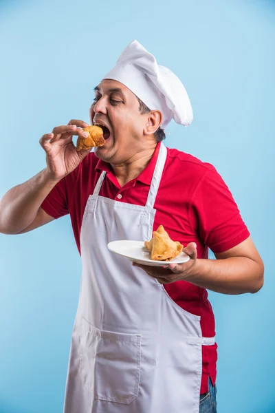 Indian male chef tasting indian snack samosa, asian male chef cook and food in plate