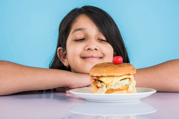 Cute indian girl eating burger, small asian girl and burger, isolated over colourful background